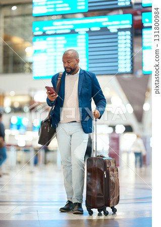 Black man with phone, luggage and checking flight schedule online, waiting in terminal for international business trip. Internet, travel app and businessman at airport for international destination. Black man with phone, luggage and checking flight schedule online, waiting in terminal for international business trip. Internet, travel app and businessman at airport for international destination. 131800984