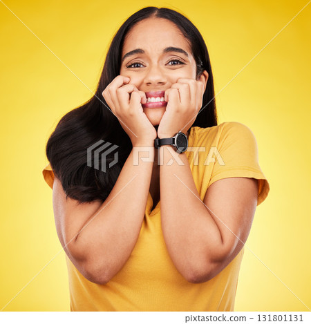 Nervous, fear portrait and woman in a studio with stress and anxiety with nail biting. Isolated, yellow background and panic of a scared person feeling terror, phobia and mental health problem 131801131