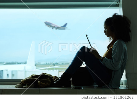 Airport, travel and black woman online with tablet by window waiting for flight, departure and transport. International plane, lobby and girl with digital tech for internet, schedule and social media Airport, travel and black woman online with tablet by window waiting for flight, departure and transport. International plane, lobby and girl with digital tech for internet, schedule and social media 131801262