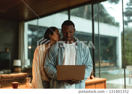 Couple enjoying intimate moment while using laptop in modern home with Scandinavian design Couple enjoying intimate moment while using laptop in modern home with Scandinavian design 131801352