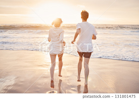 Couple at beach, running to ocean with travel and freedom outdoor, love and care in relationship with youth. Care free at sunset, nature and sea waves with young people back view on holiday in Hawaii Couple at beach, running to ocean with travel and freedom outdoor, love and care in relationship with youth. Care free at sunset, nature and sea waves with young people back view on holiday in Hawaii 131801475