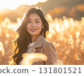A woman smiling at dusk in autumn - portrait standing in a backlit field of silver grass 131801521