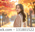 A woman smiling while being illuminated by the setting sun in a tunnel of autumn leaves 131801522