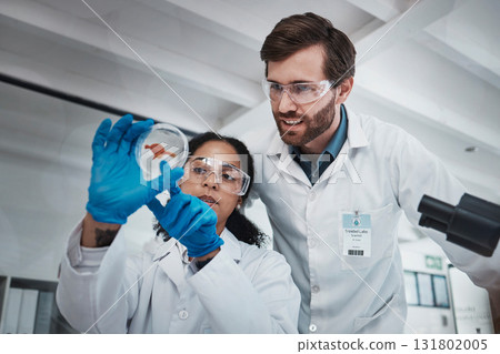 Science, analysis and scientists with a blood sample in a lab for research, dna test and healthcare. Medical, innovation and man and woman looking at a red chemical for analytics and experiment 131802005