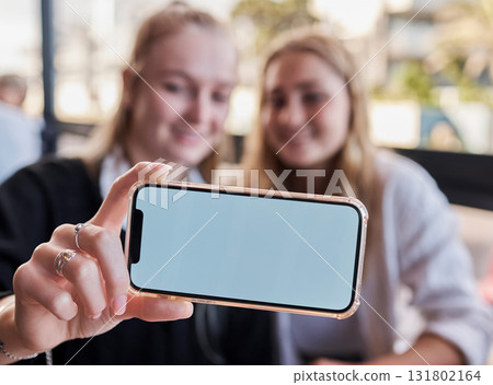 Selfie, showing and friends with mockup phone for advertising a brand at a restaurant. Marketing, contact and hands of women with a blank mobile screen for a photo, show app and social media at cafe Selfie, showing and friends with mockup phone for advertising a brand at a restaurant. Marketing, contact and hands of women with a blank mobile screen for a photo, show app and social media at cafe 131802164