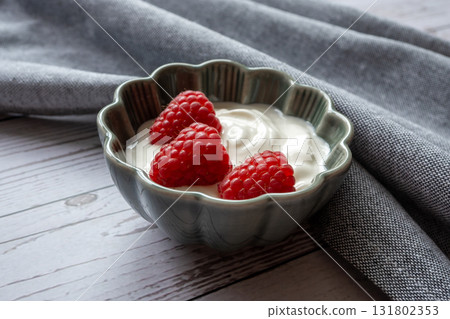 Natural white yogurt with red raspberry berries in green plate, wood table and napkin for healthy breakfast. Natural white yogurt with red raspberry berries in green plate, wood table and napkin for healthy breakfast. 131802353
