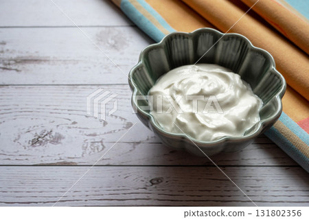 Natural white greek yogurt in porcelain green plate on the wood table with napkin for healthy breakfast. Food concept. Space for text. Natural white greek yogurt in porcelain green plate on the wood table with napkin for healthy breakfast. Food concept. Space for text. 131802356