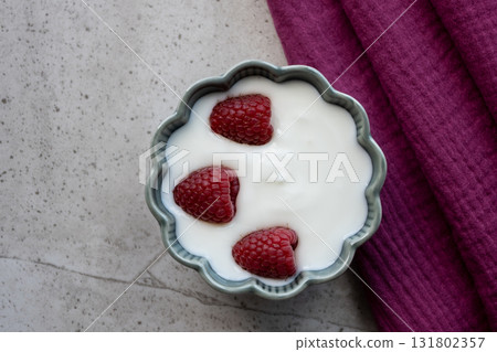 Natural white yogurt with raspberry berries in green plate, wood table and napkin for healthy breakfast.  131802357