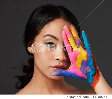 Beauty, woman and face, paint on palm with art, colorful aesthetic and makeup with color in portrait on studio background. Skin, glow and cosmetics, creativity and female hand with artistic 131802410