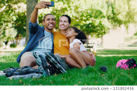 Interracial family selfie, girl and park with rollerblades, bonding or smile for profile picture, happy or holiday. Black man, mom and child for happiness, hug or diversity for social media on grass Interracial family selfie, girl and park with rollerblades, bonding or smile for profile picture, happy or holiday. Black man, mom and child for happiness, hug or diversity for social media on grass 131802416