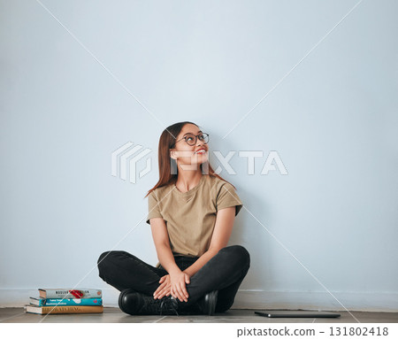 Textbook thinking, student woman and smile by a wall with school notes for learning with happiness. University, college and house with floor sitting of a happy person ready for studying with mockup 131802418