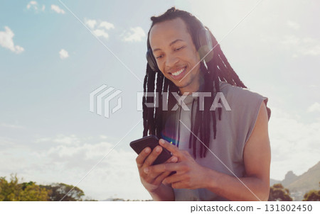 Sky, black man and smartphone with headphones streaming music, online reading and podcast outdoor. African American male, guy and cellphone for social media, headset and listen to audio and sounds 131802450