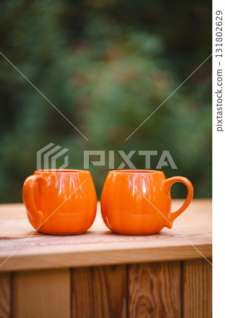 two pumpkin-shaped mugs on a rustic tabletop 131802629