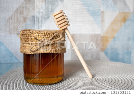 Honey glass jar with honeycomb and wood spoon stay on the table. Honey glass jar with honeycomb and wood spoon stay on the table. 131803131