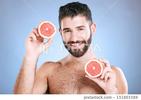 Portrait, skincare and grapefruit with a man model in studio on a blue background for natural beauty or hygiene. Fruit, wellness and nutrition with a handsome male posing to promote a healthy diet 131803389