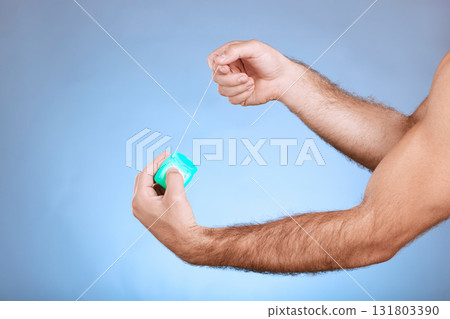 Floss, dental and man hands with container on studio mockup for teeth, mouth cleaning and marketing. Closeup of flossing product, thread and blue background for tooth cosmetics, mock up and backdrop 131803390