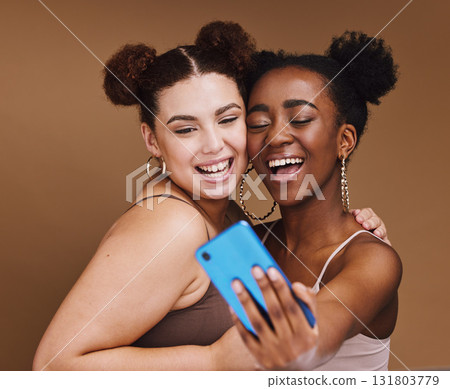 Fashion, selfie and friends with phone smile on brown background for wellness, cosmetics and makeup. Influencer, happy and black women on smartphone for social media content, picture and online post Fashion, selfie and friends with phone smile on brown background for wellness, cosmetics and makeup. Influencer, happy and black women on smartphone for social media content, picture and online post 131803779