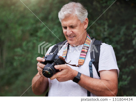 Senior man, hiking and photography with camera in forest, nature and green environment. Happy male hiker, tourist and travel photographer on trekking adventure, sightseeing journey or explore scenery 131804434