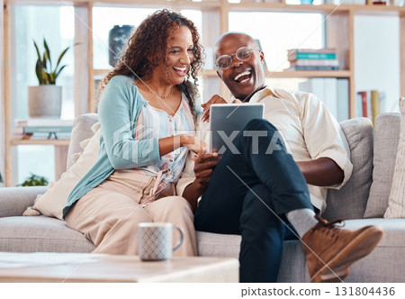 Mature couple, tablet and sofa for laugh in living room with bond, love or video on app for memory. Black man, woman and mobile touchscreen for funny movie on web in house on lounge couch to relax Mature couple, tablet and sofa for laugh in living room with bond, love or video on app for memory. Black man, woman and mobile touchscreen for funny movie on web in house on lounge couch to relax 131804436