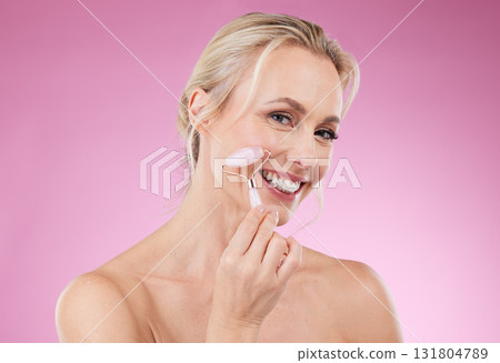 Beauty, face roller and portrait of woman doing facial massage for dermatology and cosmetics. Happy aesthetic person on pink background for skincare, self care and rose quartz results for health glow 131804789
