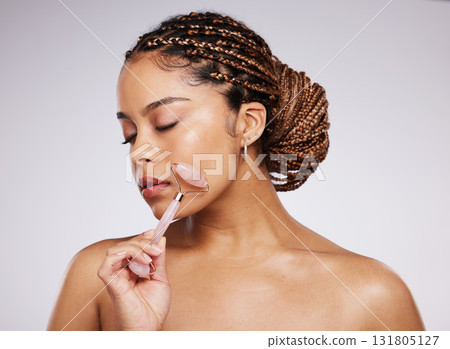 Girl, beauty or face massage with roller, facial product for healthy skincare on studio background. Model, crystal stone treatment or wellness for natural cosmetics, rose quartz dermatology in salon Girl, beauty or face massage with roller, facial product for healthy skincare on studio background. Model, crystal stone treatment or wellness for natural cosmetics, rose quartz dermatology in salon 131805127