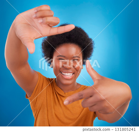 Finger framing, portrait and happy black woman on blue background, studio and backdrop. Face, female and hands frame perspective, pose and smile of happiness, photography or capture profile picture 131805241
