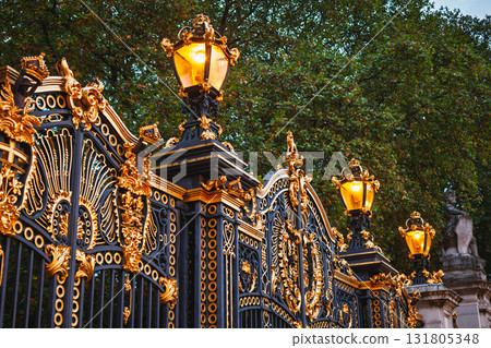 Ornate golden gates illuminated at dusk near Buckingham Palace along The Mall in London 131805348