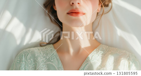 Soft morning light casting gentle shadows on a serene woman's face as she rests in an elegant patterned robe on white bedding, AI Generative 131805595