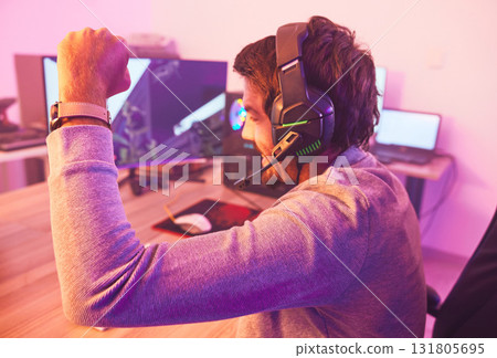 Winner, fist and man on computer with microphone, celebrating game win and success. Happy male gamer, cheering or esport player celebration for online competition, excited for progress or achievement Winner, fist and man on computer with microphone, celebrating game win and success. Happy male gamer, cheering or esport player celebration for online competition, excited for progress or achievement 131805695