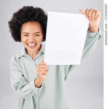 Portrait, poster and mockup with a woman holding blank paper in studio on a gray background for branding. Marketing, smile or product placement with a happy young afro female showing advertising copy Portrait, poster and mockup with a woman holding blank paper in studio on a gray background for branding. Marketing, smile or product placement with a happy young afro female showing advertising copy 131805867