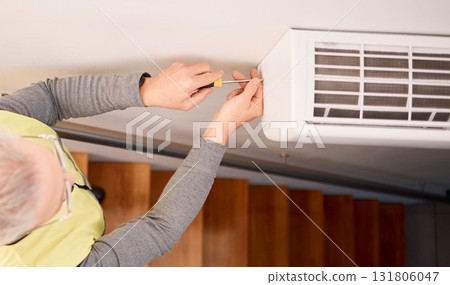 Service, installation and above of a man with an air conditioner, maintenance and ac repair. Building, contractor and a handyman fitting a tool on a wall of a home for home improvement and heat 131806047