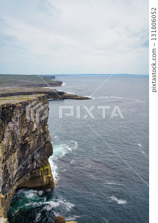 Scenic view of the Irish coastline, with rugged cliffs overlooking the vast Atlantic Ocean under a cloudy sky. Scenic view of the Irish coastline, with rugged cliffs overlooking the vast Atlantic Ocean under a cloudy sky. 131806052