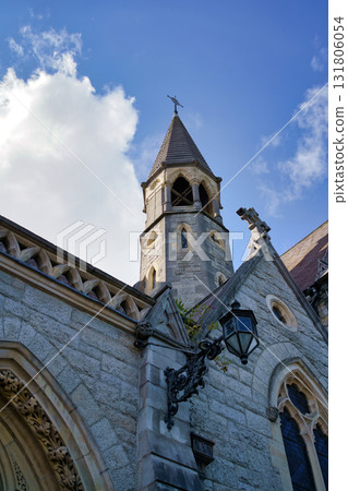An architectural detail of a historic building in Dublin, Ireland, showcasing its stone facade and a bell tower under a bright blue sky. 131806054