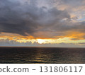 Dramatic sunset over the ocean with stormy clouds. Golden sunlight breaking through the dark sky and reflecting on the water 131806117