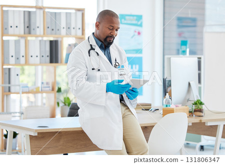 Black man, doctor and tablet in healthcare research, planning or checking schedule appointment at hospital. Happy African male medical professional working and browsing on touchscreen for Telehealth 131806347