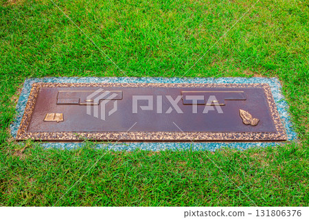 Bronze memorial plaque resting on lush green grass, honoring cherished individuals in peaceful cemetery 131806376