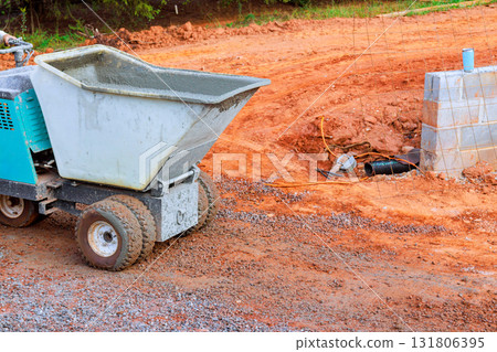 Small concrete mixer is on construction site, using concrete wheelbarrow buggy truck 131806395