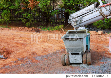 Concrete mixer pours new cement into dumper wheelbarrow buggy truck on construction site Concrete mixer pours new cement into dumper wheelbarrow buggy truck on construction site 131806404
