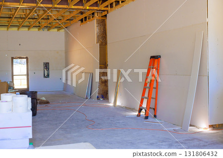 Workers are busy setting up drywall in an unfinished room with an ladder 131806432