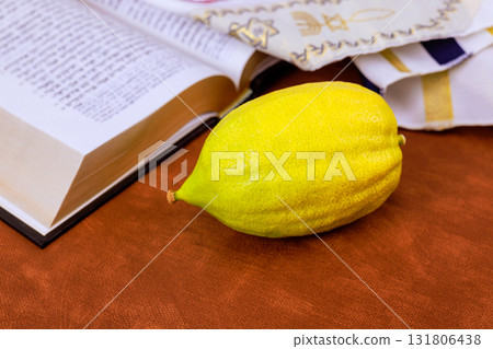 Yellow etrog citron fruit on open Hebrew prayer book Torah text during Jewish holiday of Sukkot against traditional religious text. Tanakh prayer holy book 131806438