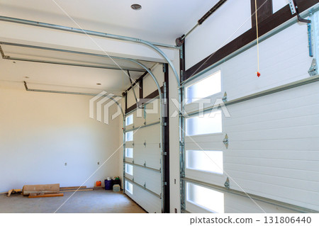 Bright garage space features two large roll up doors simple walls, perfect for storage room 131806440