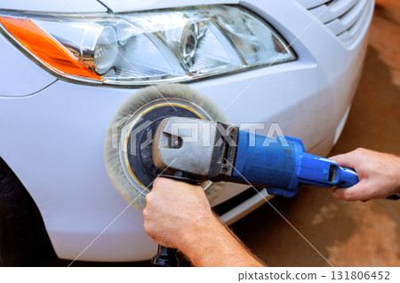 Person is polishing front of white car using buffer power tool to enhance its shine cleanliness. Person is polishing front of white car using buffer power tool to enhance its shine cleanliness. 131806452