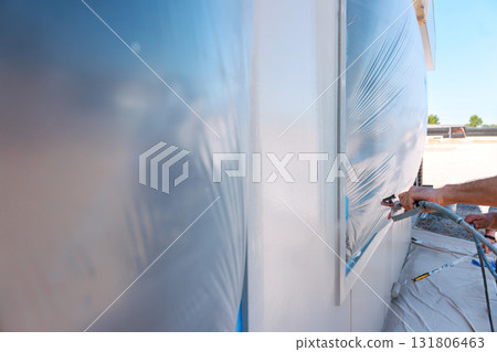 Spray painting is taking place at construction site as workers apply paint 131806463