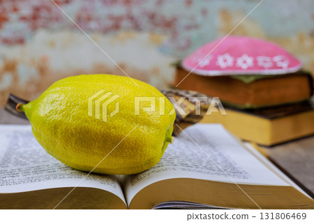 Traditional Jewish etrog citrus fruit displayed on open prayer book prayer shawl with Star of David pattern during Sukkot holiday ritual. 131806469