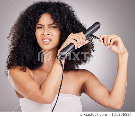 Sad, face portrait and woman with hair straightener in studio isolated on gray background. Haircare damage, hairloss and black female model angry with flat iron for hairstyle after salon treatment. Sad, face portrait and woman with hair straightener in studio isolated on gray background. Haircare damage, hairloss and black female model angry with flat iron for hairstyle after salon treatment. 131806525