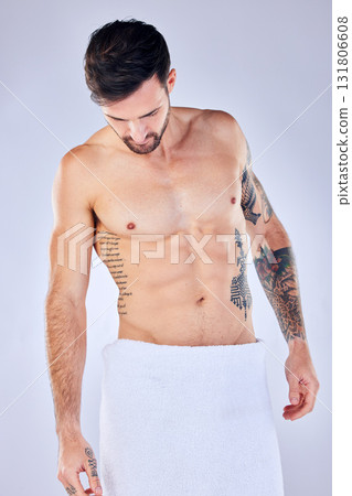 Body, health and man in towel in studio after shower, cleaning or bathing for hygiene and wellness isolated on a gray background. Topless, body art and male fitness model with tattoos, abs and muscle Body, health and man in towel in studio after shower, cleaning or bathing for hygiene and wellness isolated on a gray background. Topless, body art and male fitness model with tattoos, abs and muscle 131806608