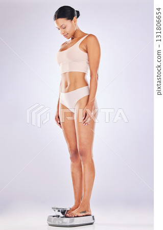 Weightloss, fitness and woman weighing on a scale for health, wellness or diet isolated in a studio white background. BMI, athlete and female measure or checking body mass after exercise or workout 131806654
