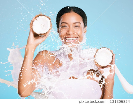 Beauty, skin care and woman with coconut for healthy skin and diet on a blue background. Face of happy aesthetic model person with milk splash and fruit for sustainable facial health and wellness 131806834