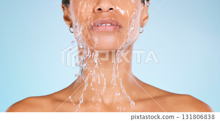 Face, water and cleaning with a black woman in studio on a blue background for hygiene or hydration. Splash, shower and bathroom with a young female washing her body for natural skincare or wellness 131806838