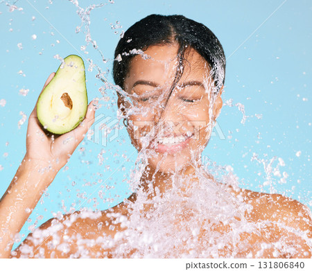Beauty, water splash and woman with avocado for healthy skin and diet on a blue background. Face of aesthetic model person with skin care and green food for sustainable facial health and wellness 131806840